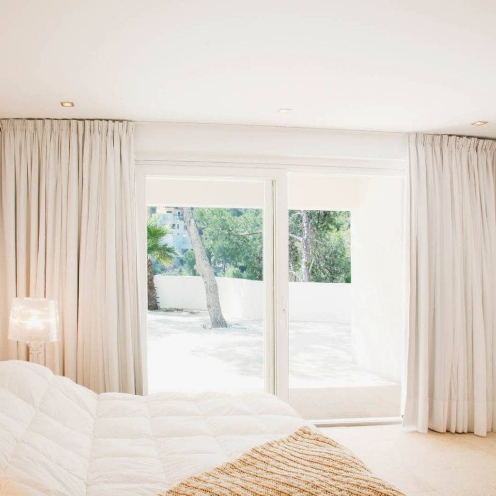 sunny bedroom with curtains on large windows